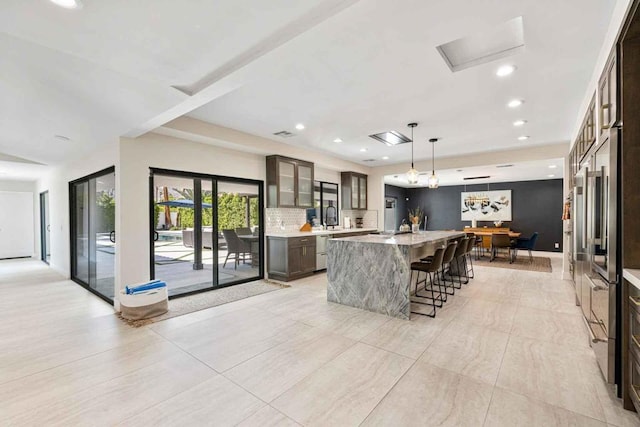 kitchen with a spacious island, sink, decorative light fixtures, a kitchen bar, and dark brown cabinetry