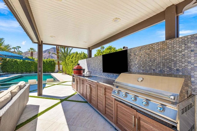 view of patio featuring an outdoor hangout area, area for grilling, sink, grilling area, and a fenced in pool