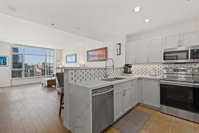 kitchen with kitchen peninsula, white cabinetry, sink, and appliances with stainless steel finishes