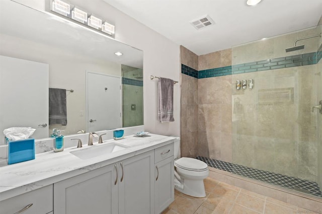 bathroom featuring tiled shower, tile patterned floors, vanity, and toilet