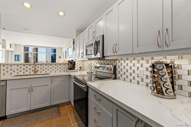 kitchen featuring gray cabinetry, dark tile patterned flooring, sink, tasteful backsplash, and stainless steel appliances