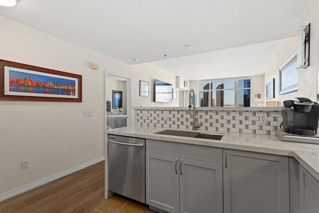 kitchen featuring light stone countertops, tasteful backsplash, gray cabinetry, sink, and dishwasher