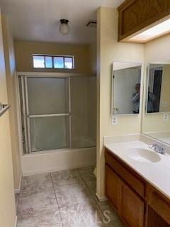 bathroom with combined bath / shower with glass door, vanity, and tile patterned floors