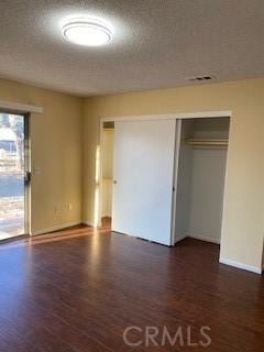 unfurnished bedroom with dark wood-type flooring, a textured ceiling, and a closet