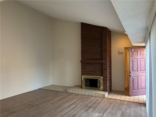 unfurnished living room featuring a fireplace, a textured ceiling, and light wood-type flooring