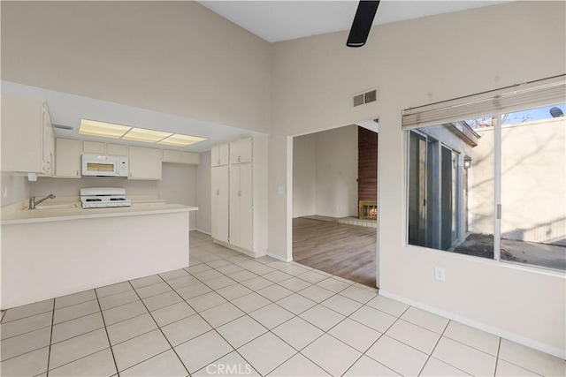 kitchen featuring sink, light tile patterned floors, stove, white cabinets, and kitchen peninsula