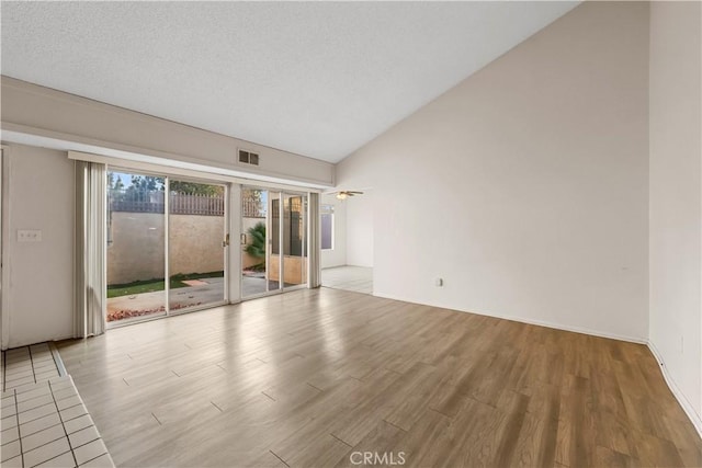 empty room featuring lofted ceiling, a textured ceiling, and light hardwood / wood-style flooring