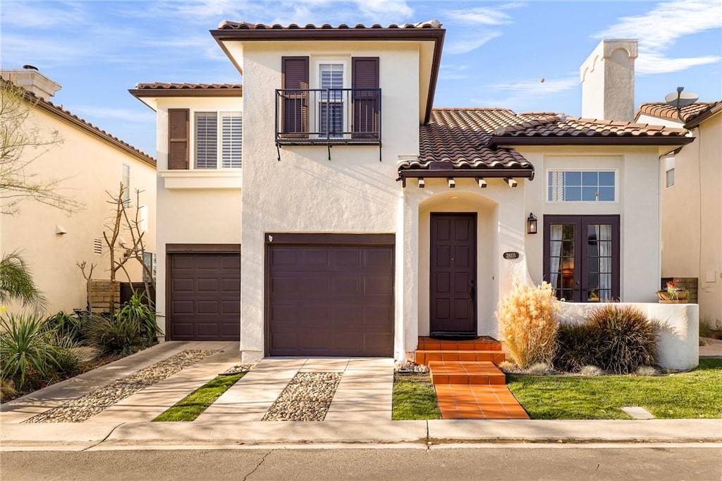 mediterranean / spanish-style home featuring a garage and a balcony