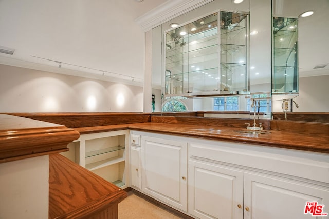 bar with wooden counters, white cabinets, crown molding, and sink