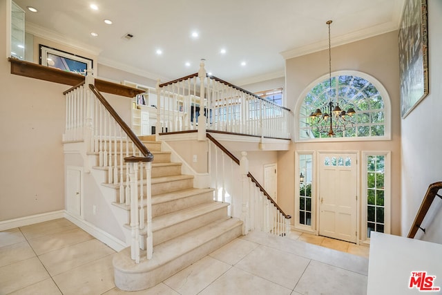 entrance foyer with a chandelier, tile patterned floors, and ornamental molding