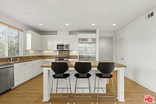 kitchen with appliances with stainless steel finishes, a center island, sink, and white cabinets