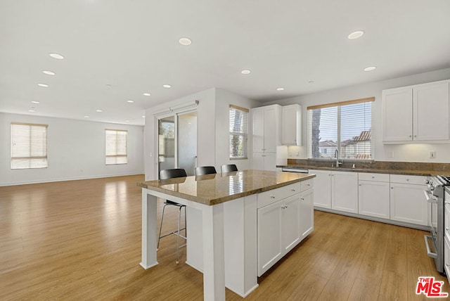 kitchen with a breakfast bar, sink, a kitchen island, and white cabinets