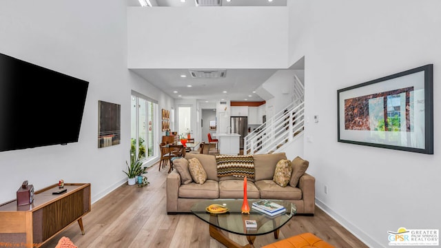 living room featuring light hardwood / wood-style flooring and a high ceiling