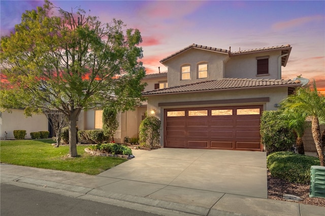 mediterranean / spanish home with a garage and a lawn