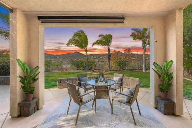 patio terrace at dusk featuring a mountain view and a yard