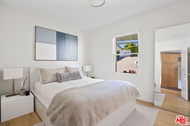 bedroom featuring hardwood / wood-style floors and refrigerator