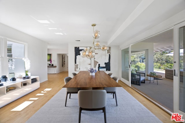 dining space with light wood-type flooring, a wealth of natural light, and a notable chandelier