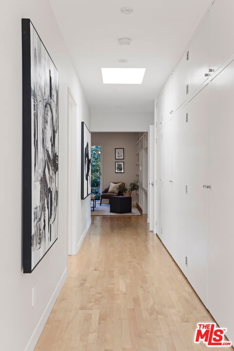 corridor with a skylight and light hardwood / wood-style floors