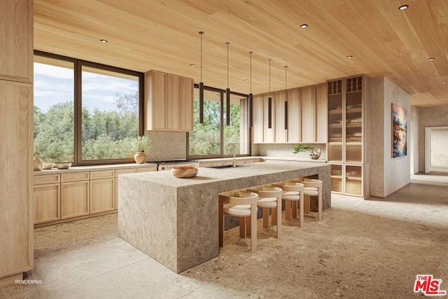 kitchen with wooden ceiling, sink, an island with sink, light brown cabinetry, and a kitchen bar