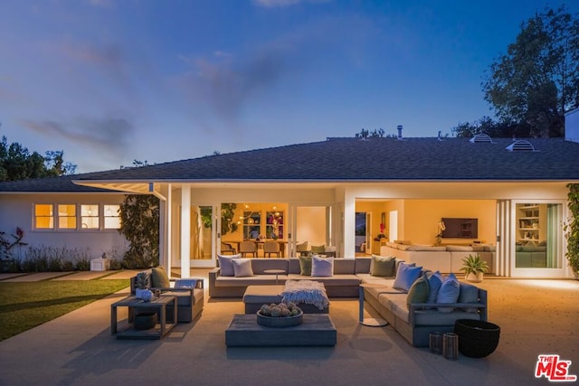 back house at dusk featuring a patio area and an outdoor living space