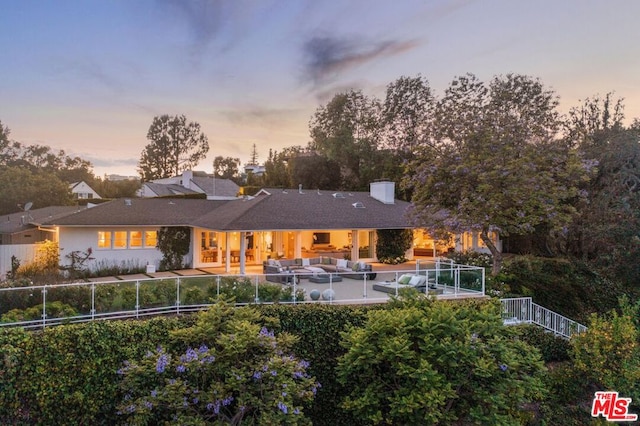 back house at dusk with outdoor lounge area and a patio