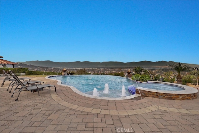 view of swimming pool with a mountain view, pool water feature, an in ground hot tub, and a patio area