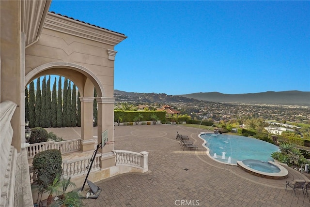 view of swimming pool featuring pool water feature, a mountain view, a patio area, and an in ground hot tub