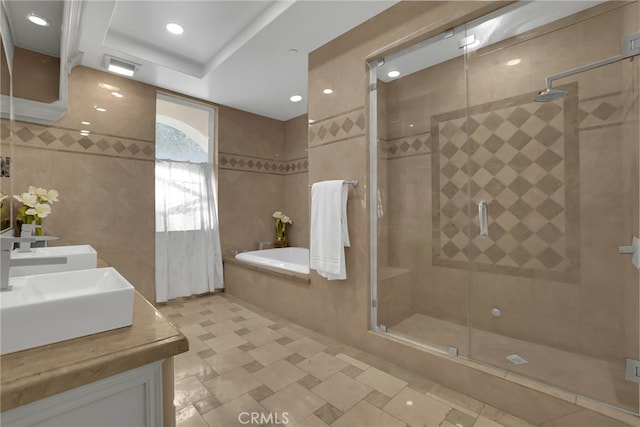 bathroom featuring vanity, tile walls, and independent shower and bath