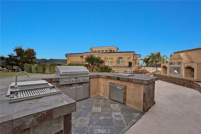 view of patio featuring an outdoor kitchen, a grill, and an outdoor fireplace