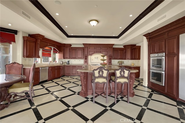 kitchen with a kitchen breakfast bar, a center island, a tray ceiling, and stainless steel appliances