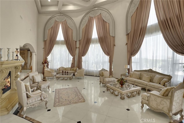 living area with plenty of natural light, a towering ceiling, coffered ceiling, and tile patterned flooring