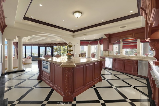 kitchen featuring a raised ceiling, stainless steel dishwasher, decorative columns, crown molding, and a kitchen island