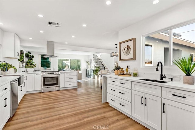 kitchen with stainless steel appliances, white cabinets, island range hood, and sink