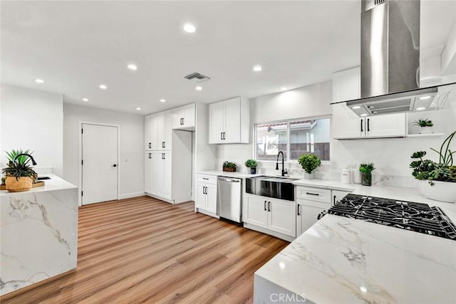 kitchen featuring island exhaust hood, light stone counters, white cabinets, stainless steel dishwasher, and sink