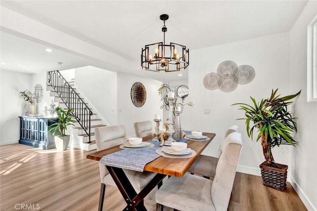 dining space with hardwood / wood-style flooring and a notable chandelier