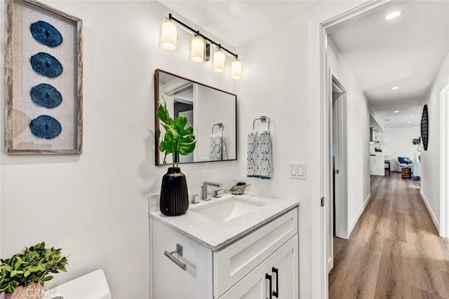 bathroom with toilet, hardwood / wood-style flooring, and vanity