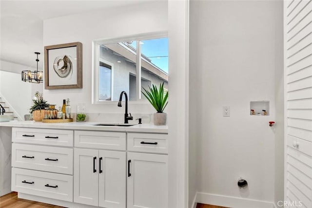 bar with sink, white cabinetry, light wood-type flooring, and pendant lighting