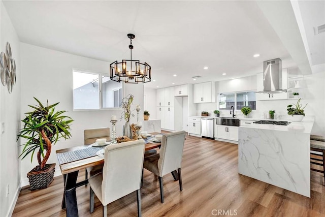 dining area featuring light hardwood / wood-style floors, an inviting chandelier, and sink