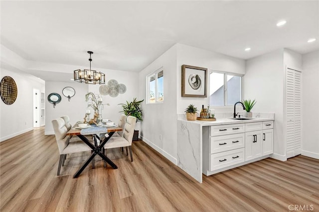 dining area featuring plenty of natural light, light wood-type flooring, a chandelier, and sink