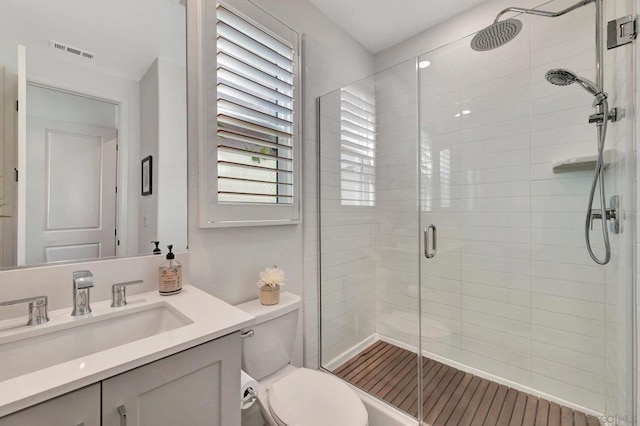 bathroom with toilet, an enclosed shower, and vanity