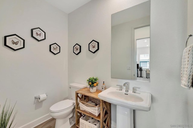 bathroom featuring toilet, sink, and hardwood / wood-style floors