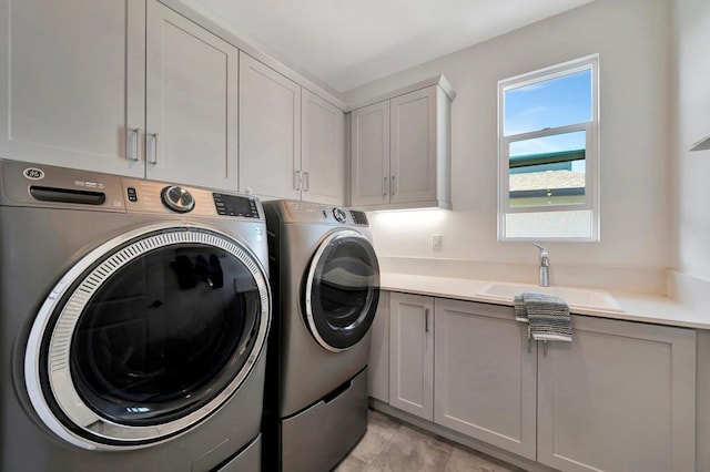 laundry room featuring washer and dryer, cabinets, and sink