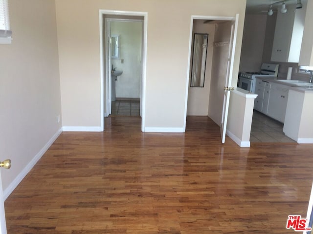 interior space with white cabinetry, dark wood-type flooring, white range with gas stovetop, and sink