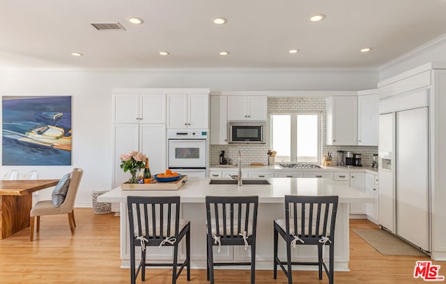 kitchen with a kitchen bar, a kitchen island with sink, sink, and appliances with stainless steel finishes