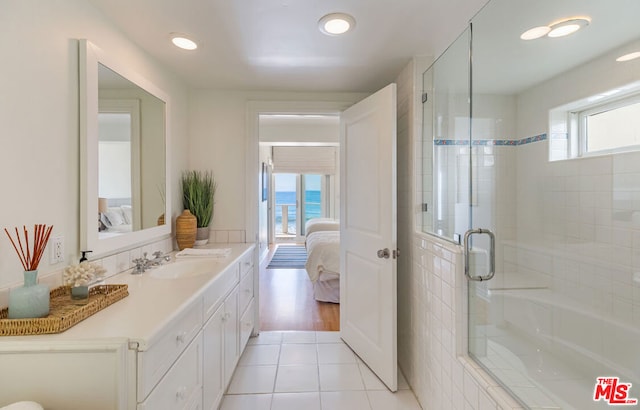 bathroom featuring vanity, a water view, tile patterned floors, and a shower with shower door