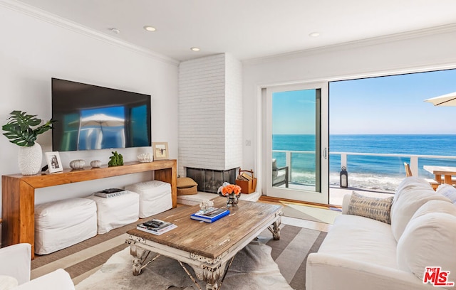 living room featuring a wealth of natural light, a fireplace, a water view, and crown molding