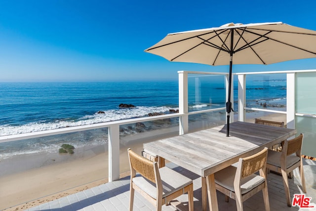 balcony featuring a view of the beach and a water view