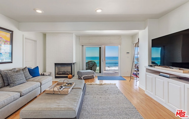 living room with light wood-type flooring and a brick fireplace