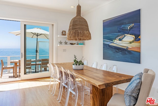 dining room with light wood-type flooring, a water view, a wealth of natural light, and crown molding