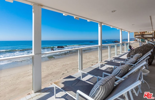 balcony with a water view and a view of the beach